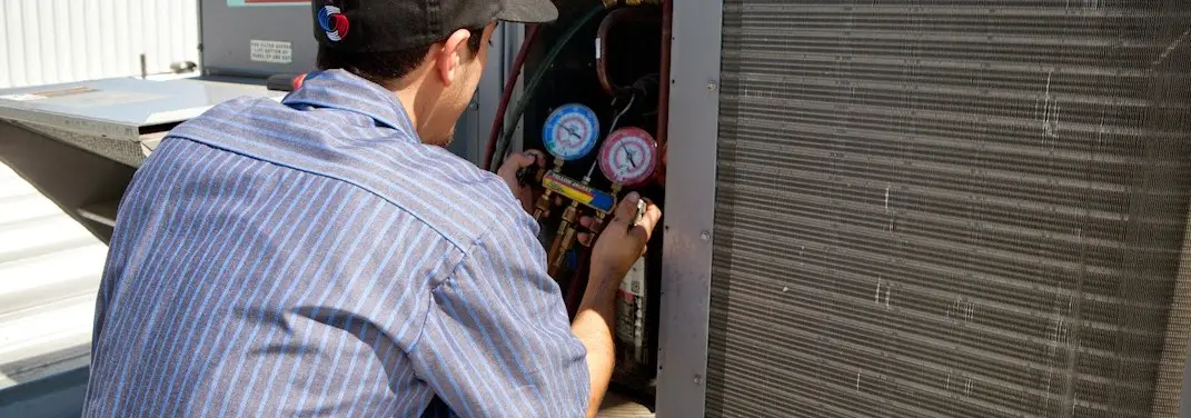 HVAC technician servicing a condenser unit in Taos