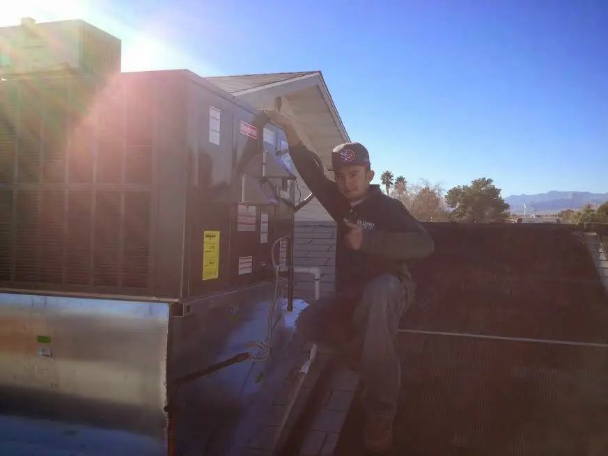 HVAC technician performing Heat Pump Repair on a rooftop unit in Taos